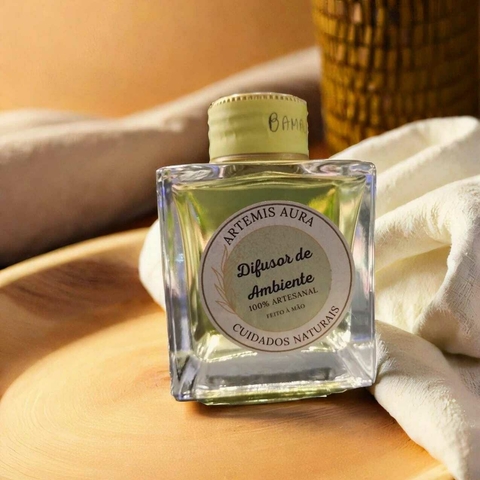 Aromatizador de ambiente em frasco de vidro, com rótulo que indica ser 100% artesanal da marca Artemis Aura.