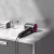 Secador de cabelo profissional Supersônico da SmartElectric® sobre uma bancada com toalhas e flores decorativas ao fundo.
