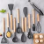 Conjunto de utensílios de cozinha de silicone com 12 peças, incluindo espátulas, colheres e batedor, em cores cinza e madeira.