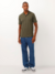 Polo Piquet Masculina em Algodão Verde Militar, com um homem usando calças jeans azuis e tênis brancos.