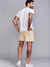 Homem de costas usando shorts de linho bege e camiseta branca, destacando suas tatuagens e o estilo casual de verão.