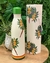Garrafa térmica de 750ml com design de arara e folhagens, na cor branca com tampa verde.