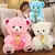Menina segurando urso de pelúcia azul com dois ursos grandes rosa e branco sentados no chão