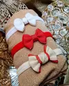 Kit de três faixinhas de bebê, Especial de Festas com laços em diferentes cores sobre um fundo dourado. Acessórios para bebês artesanais. Leve, confortável. Ateliê Mabelly Angels Celebre.