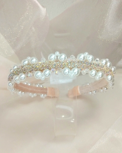 Tiara infantil Lovely com design elegante, adornada com pérolas brancas e strass brilhantes, ideal para ocasiões especiais, em fundo claro. Leve, confortável. Produto Artesanal. Ateliê Mabelly Angels Celebre.