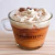 Vela capuchino en taza con crema y granos de café en la cima.