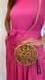 Modelo usando um vestido longo pink com detalhe de laço na cintura, segurando bolsa redonda com estampa de onça.