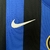 Detalhe da camisa do Inter de Milão com listras azuis e pretas, destacando o logo da Nike em branco.