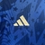 Detalhe da camisa azul royal do Cruzeiro, destacando o logo da Adidas em branco sobre um fundo com estrelas.