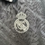 Detalhe do logo do Real Madrid em uma camisa cinza da coleção 24/25 para torcedores masculinos.
