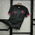 Camisa de futebol masculina do Chelsea III 24/25 na cor preta com detalhes em rosa, pendurada em um cabide.