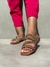 Rasteira Julia com tiras brilhantes em um fundo neutro, usada com calça rosa.