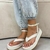 Sandália flatform branca com detalhe de tiras, usada com calça jeans clara e pé com unhas pintadas.