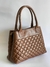 Bolsa de couro marrom com design acolchoado e alças longas.