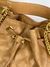 Detalhe de uma bolsa de couro bege com alça de corrente dourada e acabamento em matelassê.