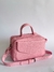 Bolsa de couro rosa com alça removível e detalhes em zíper.