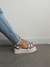 Sandália de plataforma com tiras prateadas e detalhes em pirâmide, usada com jeans claro.