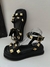 Sandálias pretas com detalhes em metal dourado, estilo moderno e elegante.