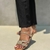 Sandália feminina com detalhes em strass, vista lateral, combinada com calça preta.