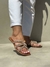 Sandálias femininas com detalhes brilhantes, usadas em um ambiente claro, com uma calça branca.