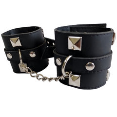 Esposas de cuero negro con cadenas y detalles metálicos.