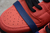 Tênis Nike SB Dunk Low 'Red Lobster' com detalhes em vermelho e azul, na lateral esquerda.