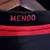 Detalhe da etiqueta da camisa retrô do Flamengo, mostrando a palavra "MENGO" em destaque.