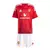 Conjunto infantil do Manchester United, composto por camisa vermelha e shorts brancos, com detalhes da Adidas e patrocínios.