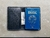Imagem da Carteira Passaporte Voyager Explorer na cor preta, aberta, com um passaporte brasileiro e uma nota de dólar visíveis.
