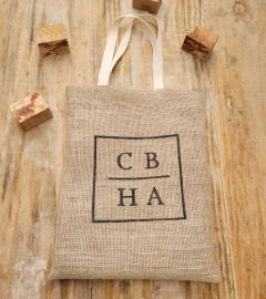 Sacola de juta natural personalizada com estampas em preto, sobre uma superfície de madeira.