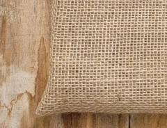 Textura de uma sacola de juta natural, mostrando o tecido em tom bege claro.