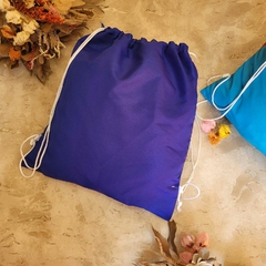 Sacola de tecido azul com cordão de ajuste formando uma mochila tipo saco. Bolsa usada para brindes corporativos. 