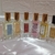 Frascos de perfumes da coleção Brand, incluindo o Tubete de Bolsa inspirado em Light Blue Dolce & Gabbana, dispostos sobre uma superfície brilhante.