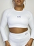 Modelo vestindo um top manga longa Selenita branco, com short da mesma coleção e em poliamida em um fundo neutro.