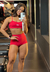Modelo posando com shorts vermelhos Garnet em uma academia, mostrando um look fitness e estiloso. Roupas fitness na promoção de black Friday e presente de natal 