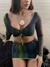 Modelo usando um top de tule da coleção Górgona, com detalhes em verde e azul, em cenário de praia.