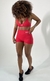 Modelo usando shorts curtos vermelhos da coleção Garnet, com top combinando e tênis escuros. Conjunto de roupas fitness com promoção de black friday 