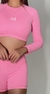 Modelo usando um conjunto rosa com camiseta de mangas longas e shorts, destacando a cor vibrante e o design moderno.