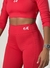 Calça Garnet vermelha modelo leggings, com detalhes em branco, combinando com um top de manga longa. Conjunto fitness em promoção na black friday, esqueta black Friday 