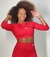 Modelo usando top manga longa vermelho da coleção Garnet, sorrindo com cabelo cacheado. Perfeito para presente de natal, e a promoção da Black Friday