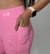 Calça leggings rosa com detalhe de bolso e logo na cintura, usada por uma modelo.