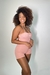 Macaquinho rosa claro em modelo ajustado, usado por uma mulher com cabelo cacheado, sorrindo e posando de lado. Whey Protein, Cupom de desconto da growth suplementos