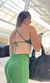 Modelo usando um top esmeralda verde, com costas nuas e calças combinando, segurando uma bolsa preta. Promoção de Black Friday