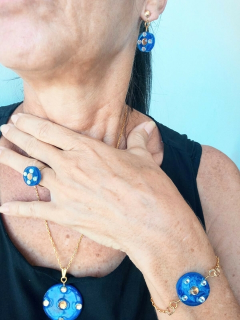 Conjunto de joias da coleção Mar de Vidro com anel, brinco, pulseira e colar em resina azul com detalhes dourados e cristais