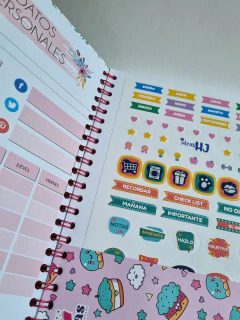 Planificador semanal, acompañado de una hoja de stickers decorativos con meses del año, iconos y frases motivacionales.