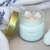 Vela perfumada Silêncio Sagrado, com cristais de quartzo branco e tampa dourada, e aroma de lavanda.