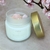 Vela perfumada Vibrando Amor de 160g em um recipiente de vidro jateado com tampa dourada, decorada com cristais rosa, e aroma de flore de cerejeira.