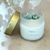Vela perfumada Pura Energia de 160g em recipiente de vidro jateado com tampa dourada, contendo pedras de quartzo verde e aroma de chá branco.