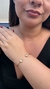 Bracelete dourado com detalhes em forma de coração, utilizado por uma modelo.