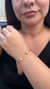 Bracelete semijoia dourado com detalhes em forma de corações cravejados, utilizado por uma modelo.